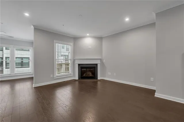 a view of an empty room with wooden floor fireplace and a window