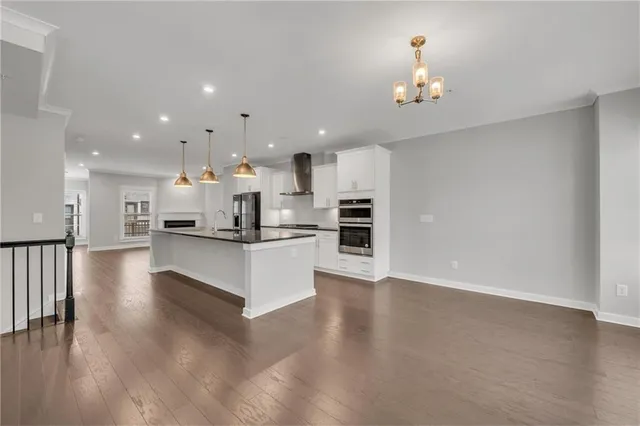a view of a kitchen with kitchen island stainless steel appliances wooden floor dining table and chairs