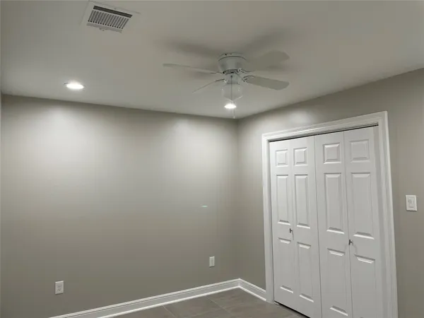 an empty room with ceiling fan and window