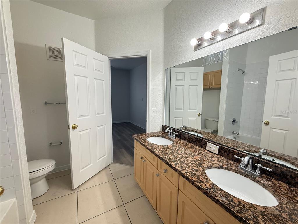 3611 Conroy Road, Unit 825 Orlando, FL 32839 - Photo 9 of 27 a spacious bathroom with a granite countertop double vanity sink a mirror and a toilet