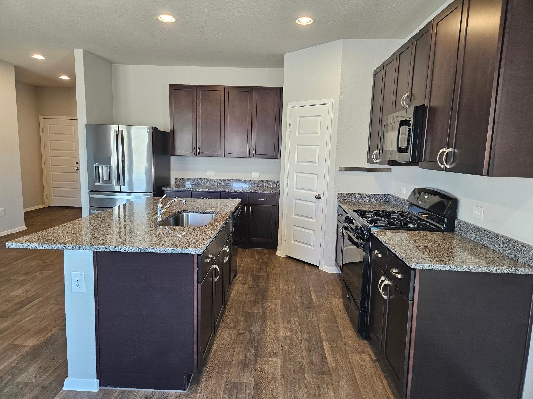 162 Hayloft Lane Elgin, TX 78621 - Photo 4 of 26 a kitchen with stainless steel appliances granite countertop a sink stove and refrigerator