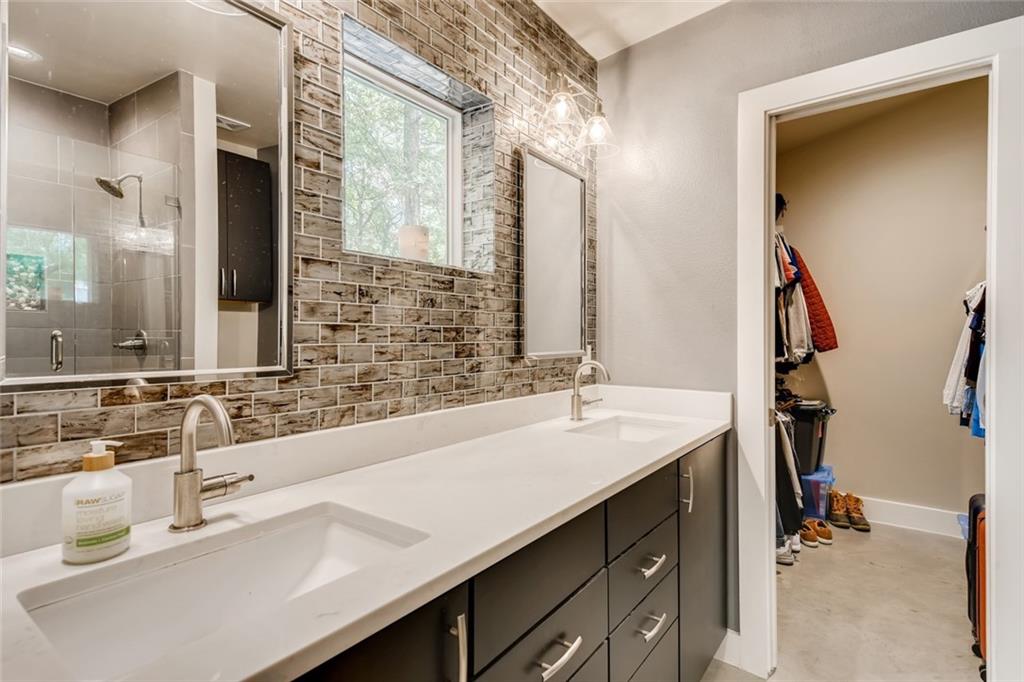 1142 Eleanor Street, Unit 2 Austin, TX 78721 - Photo 16 of 24 Double vanity with contemporary fixtures and sleek cabinetry complements the textured tile backsplash in this inviting primary bathroom.