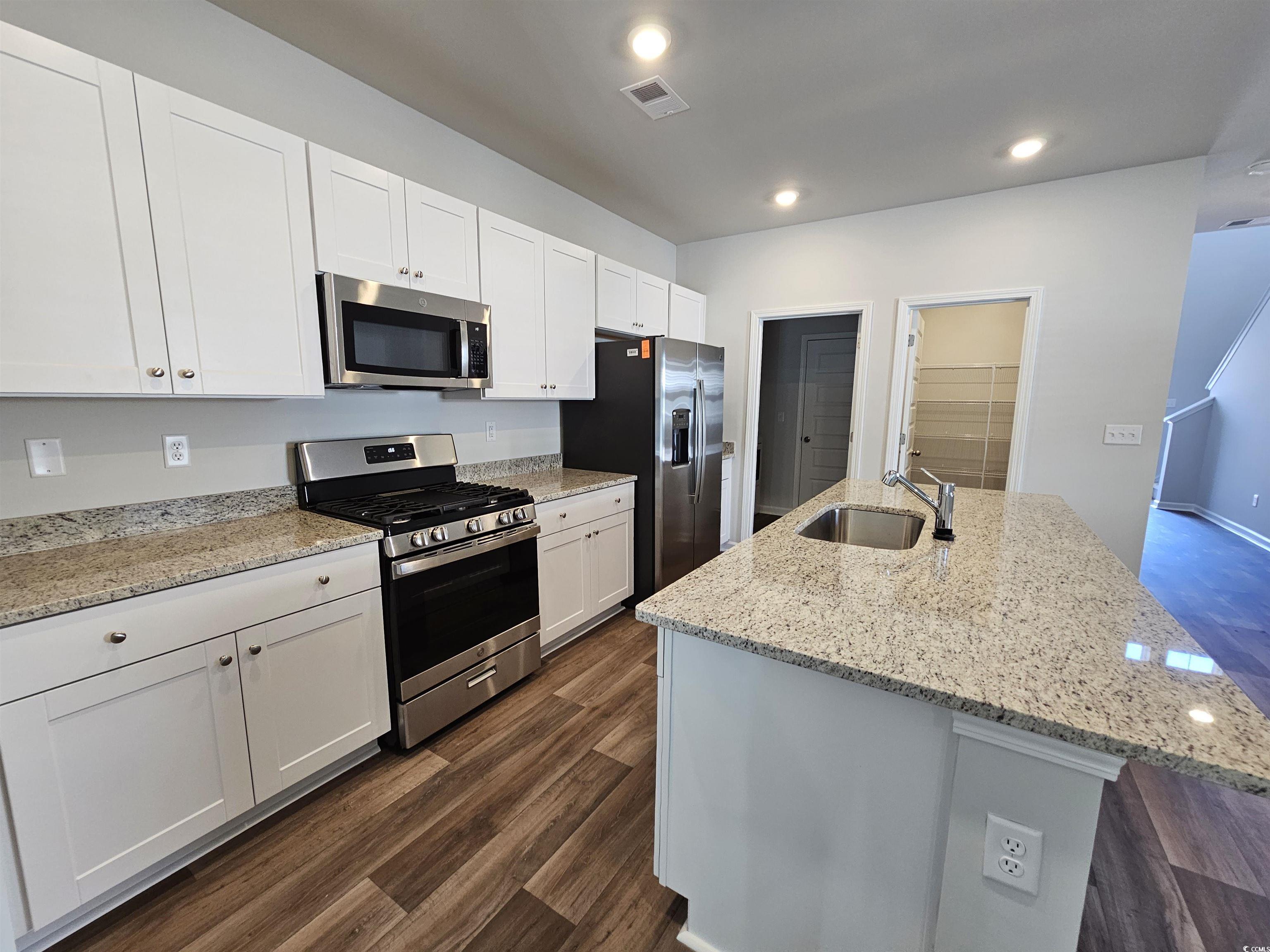 800 Wapama Street Little River, SC 29566 - Photo 5 of 34 Kitchen featuring stainless steel appliances, an island with sink, white cabinetry, light stone countertops, and recessed lighting