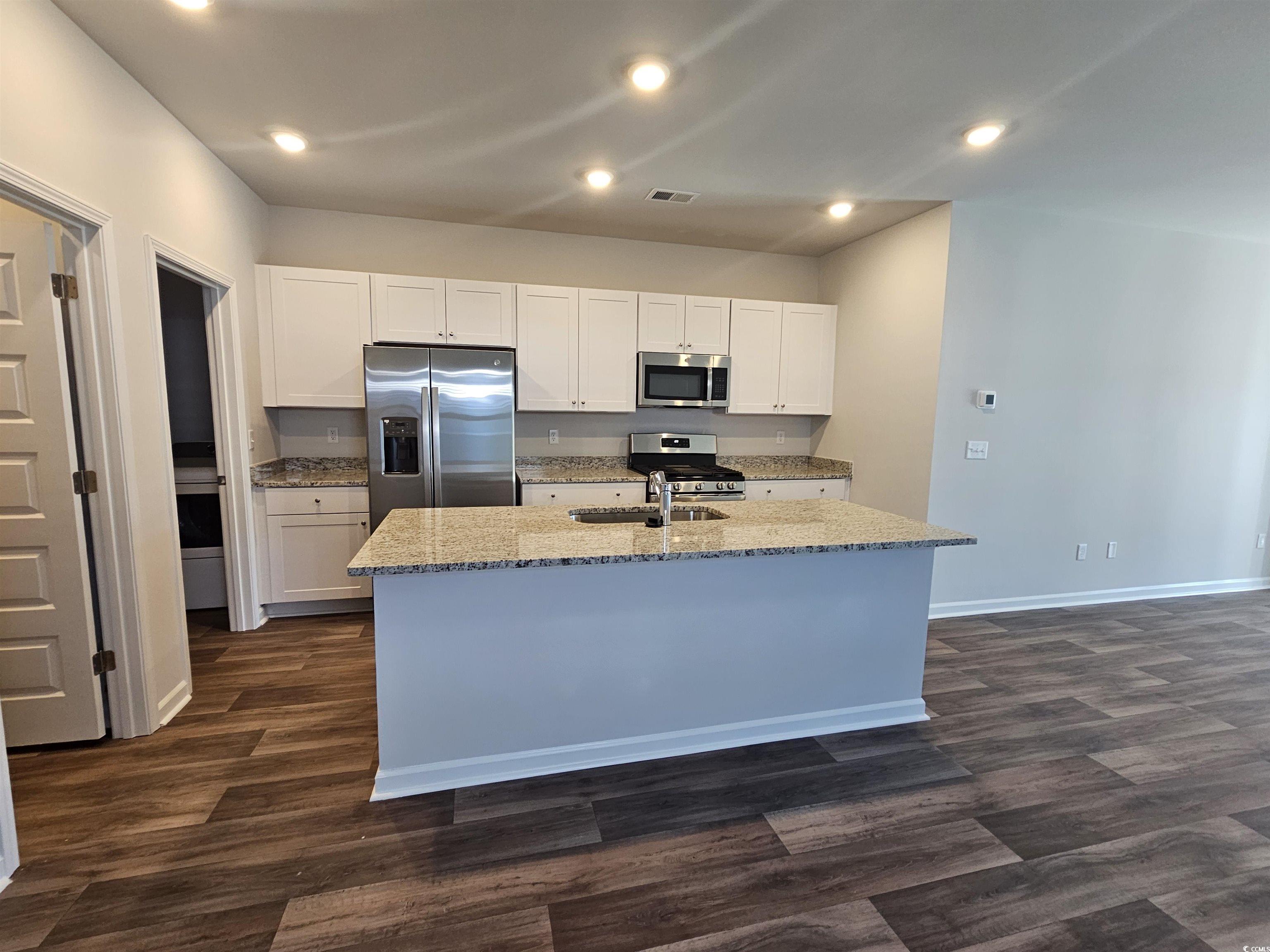 800 Wapama Street Little River, SC 29566 - Photo 6 of 34 Kitchen with light stone countertops, white cabinetry, appliances with stainless steel finishes, a center island with sink, and recessed lighting