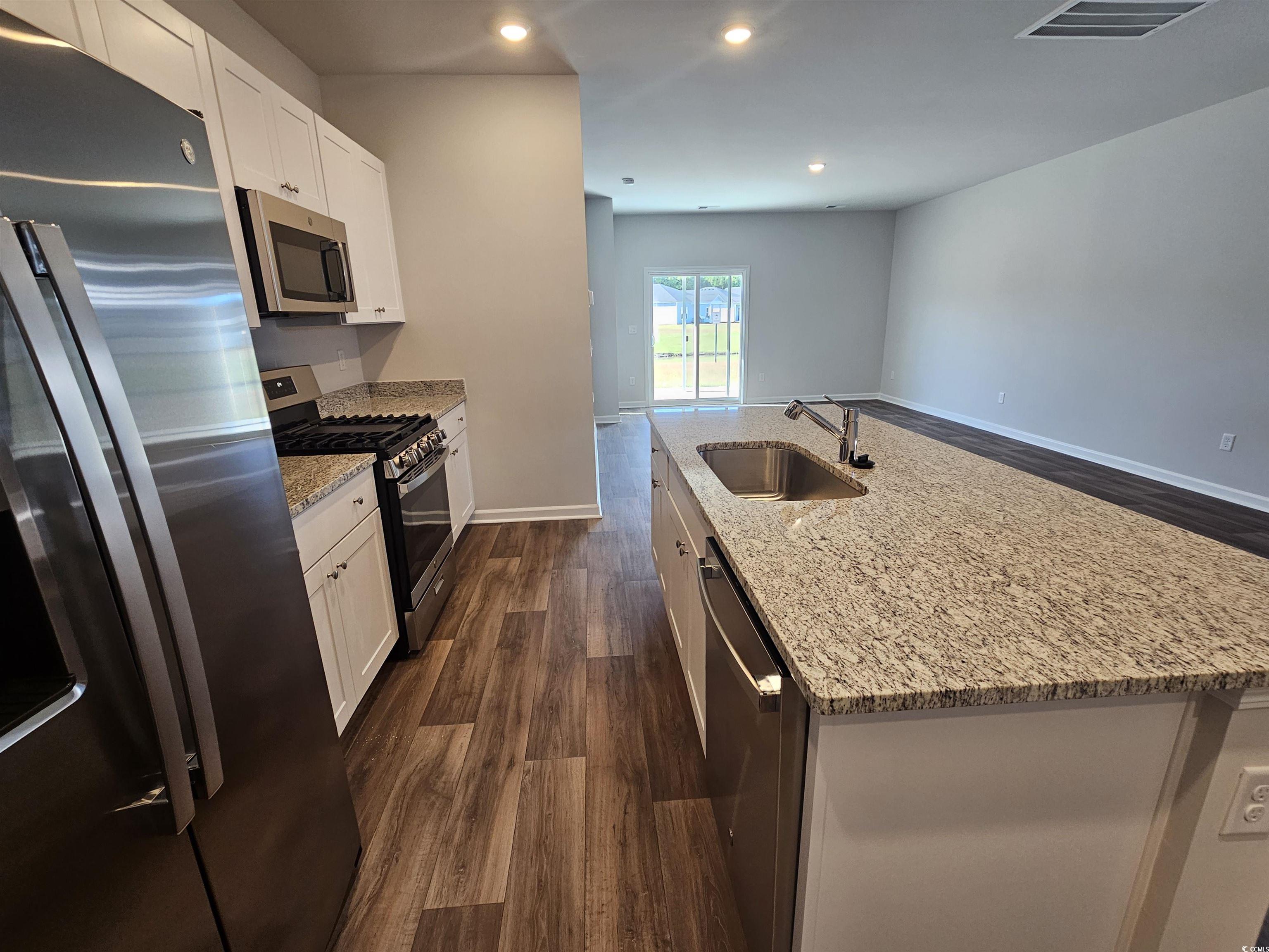 800 Wapama Street Little River, SC 29566 - Photo 7 of 34 Kitchen featuring stainless steel appliances, light stone counters, dark wood-style floors, recessed lighting, and an island with sink