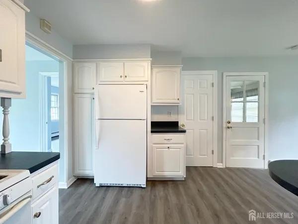 a kitchen with a refrigerator a stove top oven and white cabinets with wooden floor