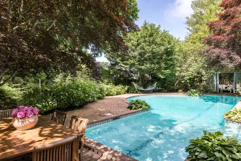 a view of a backyard house with table and chairs potted plants and large tree
