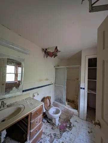a bathroom with a granite countertop sink a toilet a mirror and shower