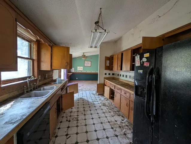 a large kitchen with granite countertop a stove refrigerator and cabinets