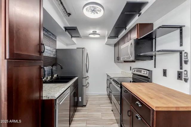 a kitchen with stainless steel appliances granite countertop a sink a stove and a refrigerator