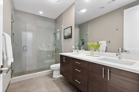 a bathroom with a double vanity sink toilet and shower