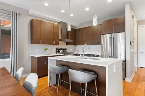 a kitchen with stainless steel appliances granite countertop a chairs a sink and a refrigerator