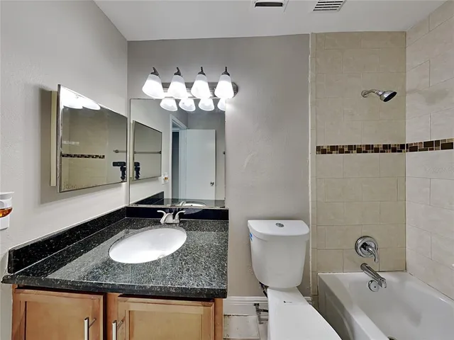 a bathroom with a granite countertop sink toilet and a mirror