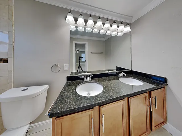 a bathroom with a granite countertop sink a toilet and a mirror