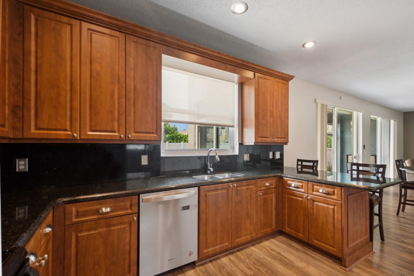 18287 Clear Brook Circle Boca Raton, FL 33498 - Photo 8 of 30 a kitchen with granite countertop wooden cabinets a sink and appliances