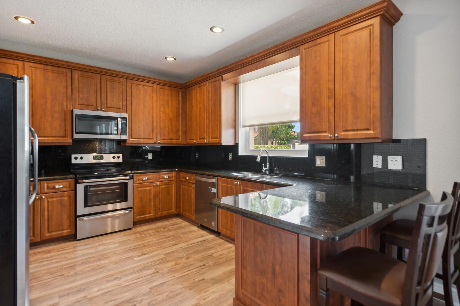18287 Clear Brook Circle Boca Raton, FL 33498 - Photo 9 of 30 a kitchen with stainless steel appliances granite countertop a stove a sink and a microwave