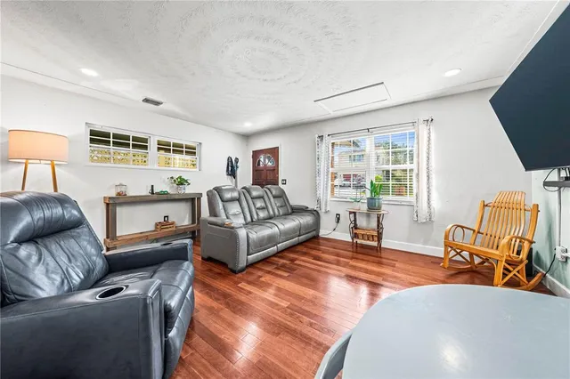 a living room with furniture and a dining table with wooden floor