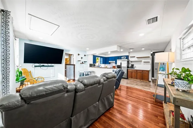 a living room with furniture and kitchen view with wooden floor