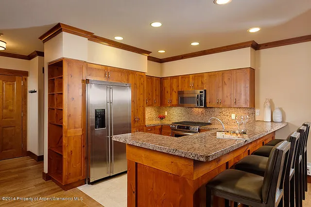 a kitchen with kitchen island granite countertop a sink and refrigerator