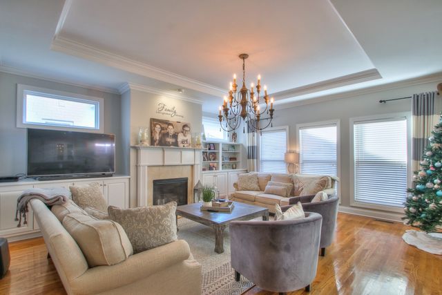 a living room with furniture a chandelier and a flat screen tv