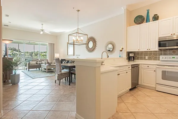 a kitchen with a sink a stove cabinets and living room view