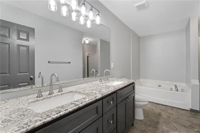 a bathroom with a granite countertop bathtub a double vanity sink and a mirror