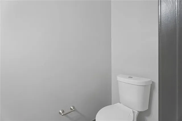 a white toilet sitting next to a white wall