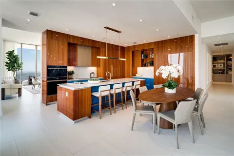 a kitchen with stainless steel appliances kitchen island granite countertop a table chairs sink and cabinets