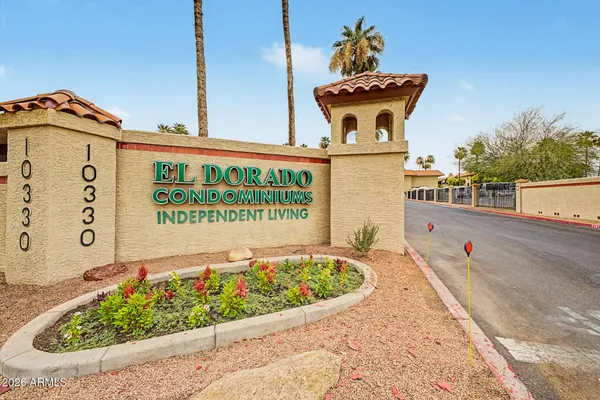 a view of a sign board with buildings in the background