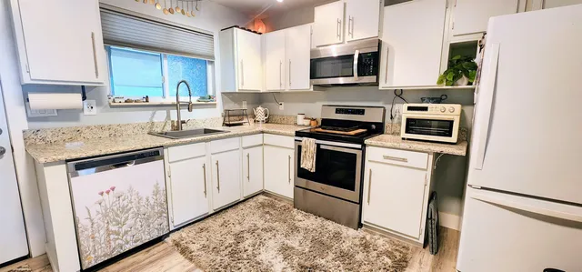 a kitchen with stainless steel appliances granite countertop a stove a sink and a microwave