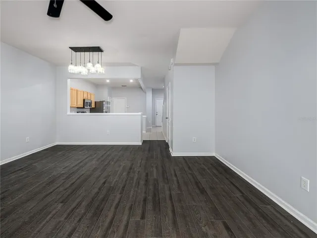 an empty room with wooden floor chandelier and windows
