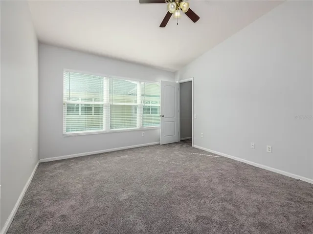 an empty room with windows and fan