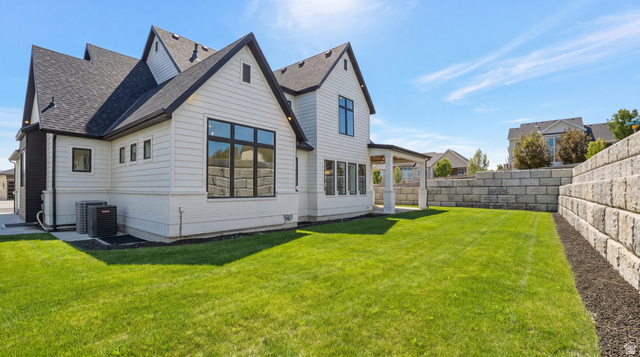 1682 North 1950 W Street, Unit 9 Provo, UT 84604 - Photo 68 of 84 Spacious backyard featuring a manicured lawn, a large retaining wall, and a covered patio area with white columns