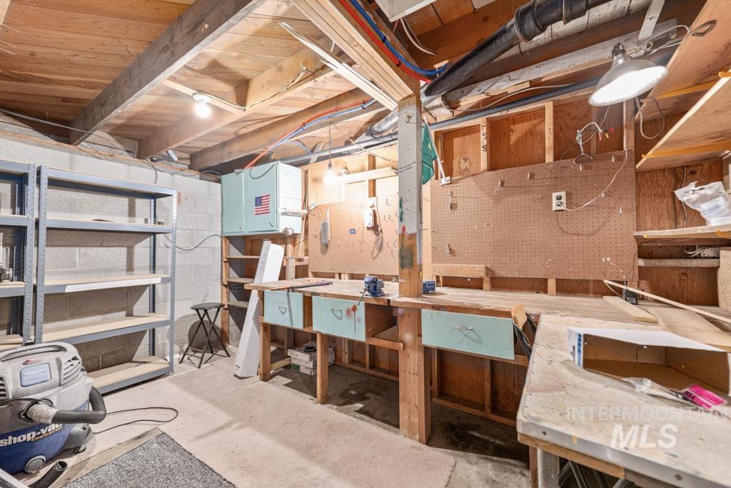 259 Highway 12 Pomeroy, WA 99347 - Photo 31 of 45 Utility space featuring a concrete floor, exposed ceiling joists, built-in shelving, and a workbench