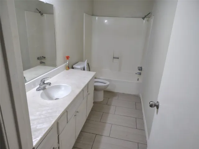 a bathroom with a granite countertop sink a toilet and shower