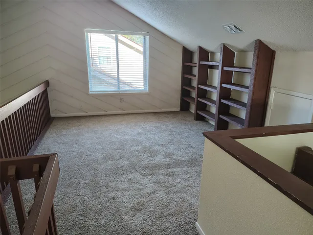 a view of an empty room with furniture and window