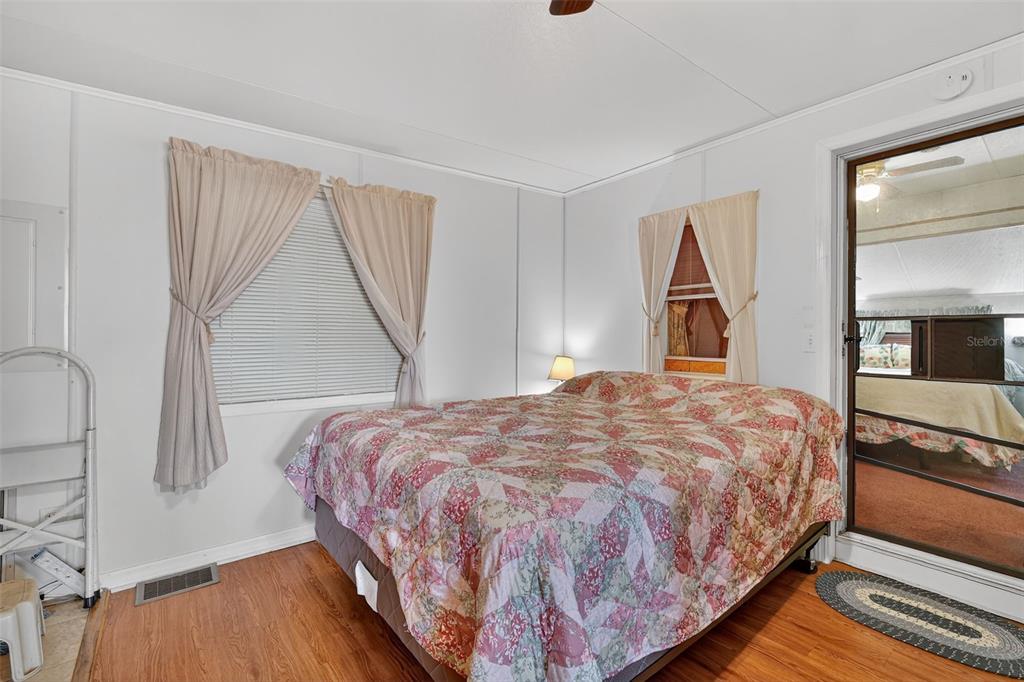 11324 Goldfinch Way Leesburg, FL 34788 - Photo 18 of 20 a bedroom with a bed and a window with wooden floor