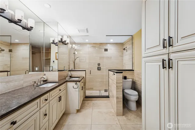 a spacious bathroom with a granite countertop sink a toilet a mirror and shower