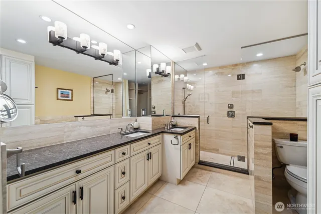 a spacious bathroom with a granite countertop sink a toilet a mirror and shower