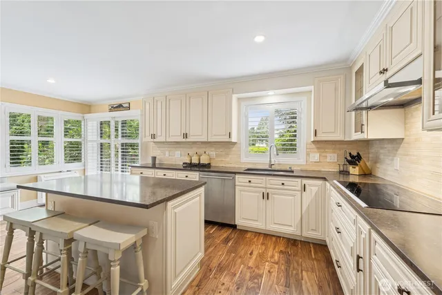 a kitchen with granite countertop a stove a sink dishwasher a refrigerator and white cabinets with wooden floor