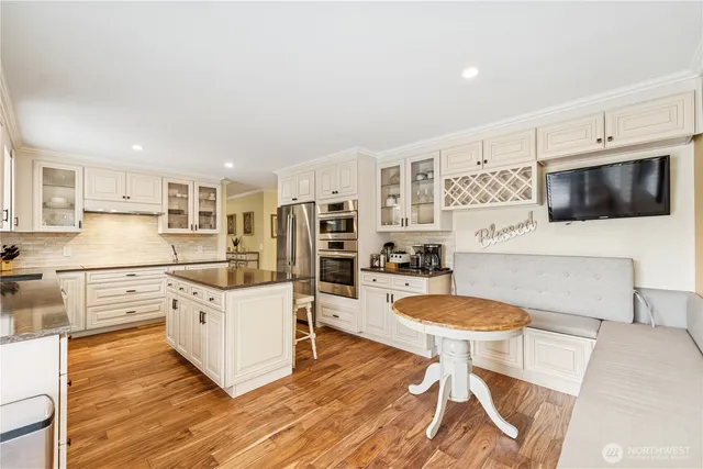 a kitchen with stainless steel appliances a microwave a stove a table and chairs