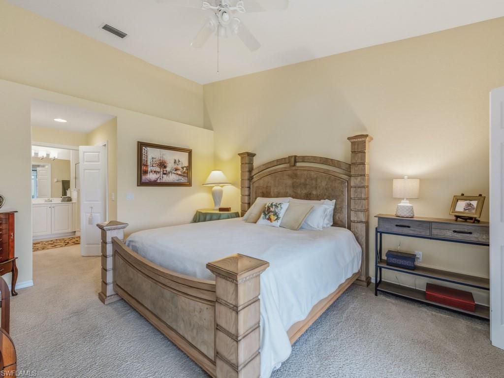 6095 Pinnacle Lane, Unit 1304 Naples, FL 34110 - Photo 11 of 47 a bedroom with a bed and a chandelier