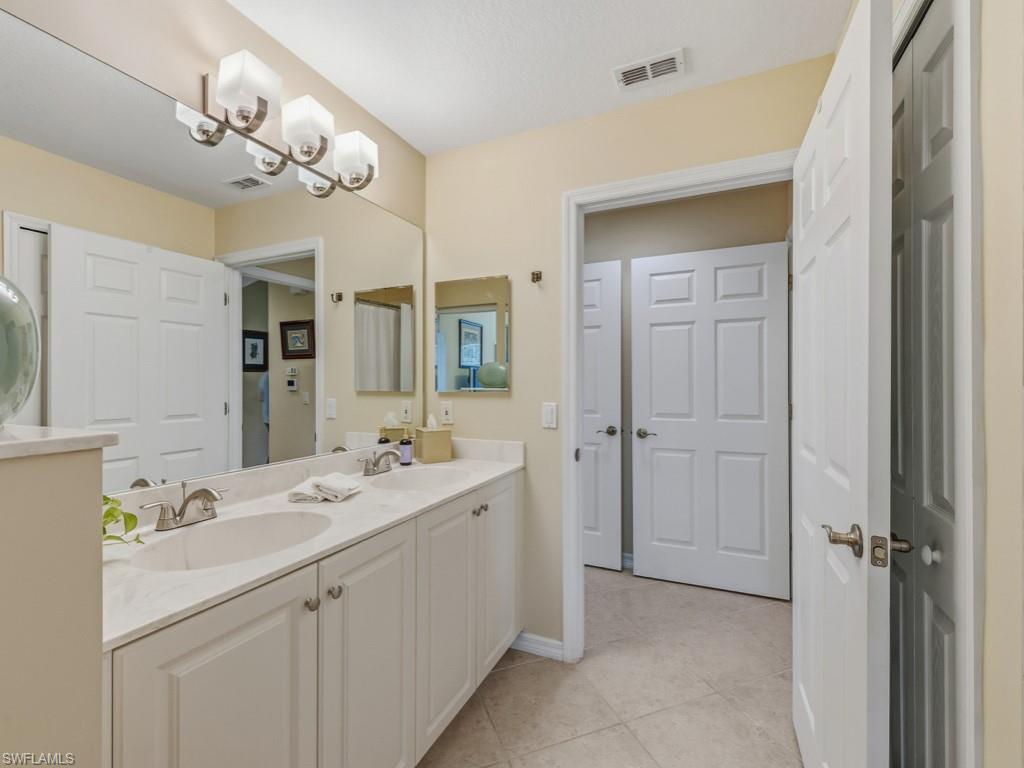 6095 Pinnacle Lane, Unit 1304 Naples, FL 34110 - Photo 18 of 47 a bathroom with a double vanity sink mirror and chandelier