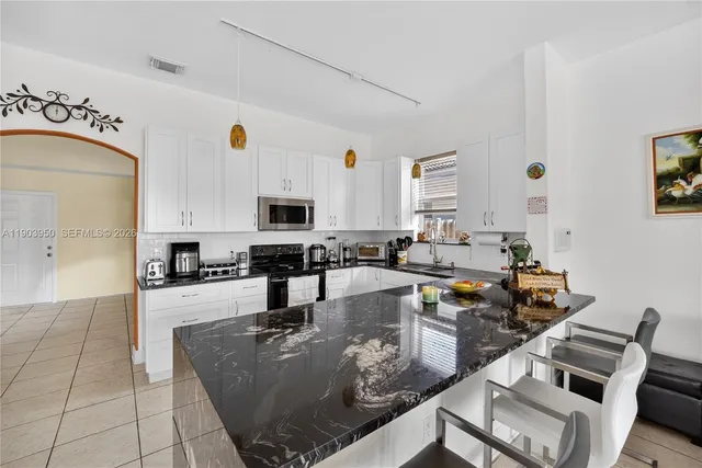 a large kitchen with stainless steel appliances granite countertop a stove and white cabinets