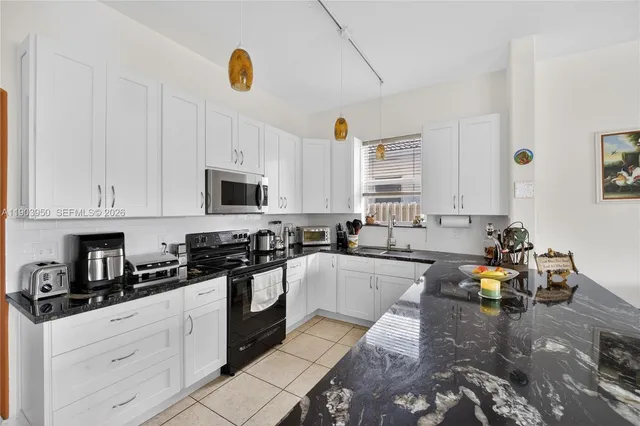 a kitchen with granite countertop a sink stainless steel appliances and cabinets