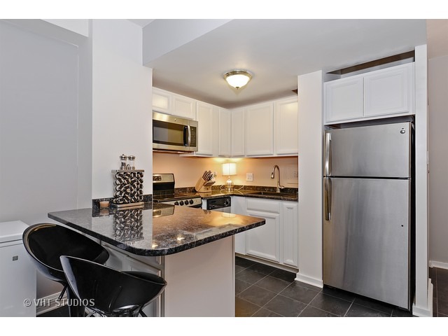 2909 North Sheridan Road, Unit 112 Chicago, IL 60657 - Photo 3 of 12 a kitchen with kitchen island a sink appliances and cabinets