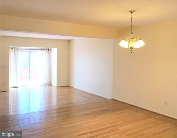 a view of a room with wooden floor chandelier and a window