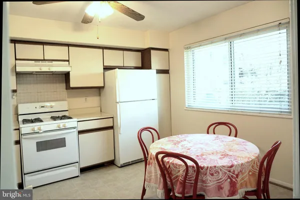 a kitchen with stainless steel appliances granite countertop a stove a refrigerator and a table with wooden floor