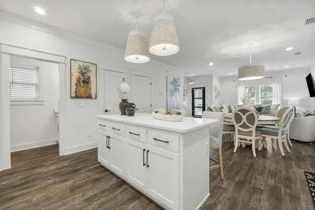 a large kitchen with cabinets a sink dishwasher a dining table and chairs with wooden floor