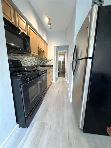 a view of a kitchen with stainless steel appliances wooden floor and wooden cabinets
